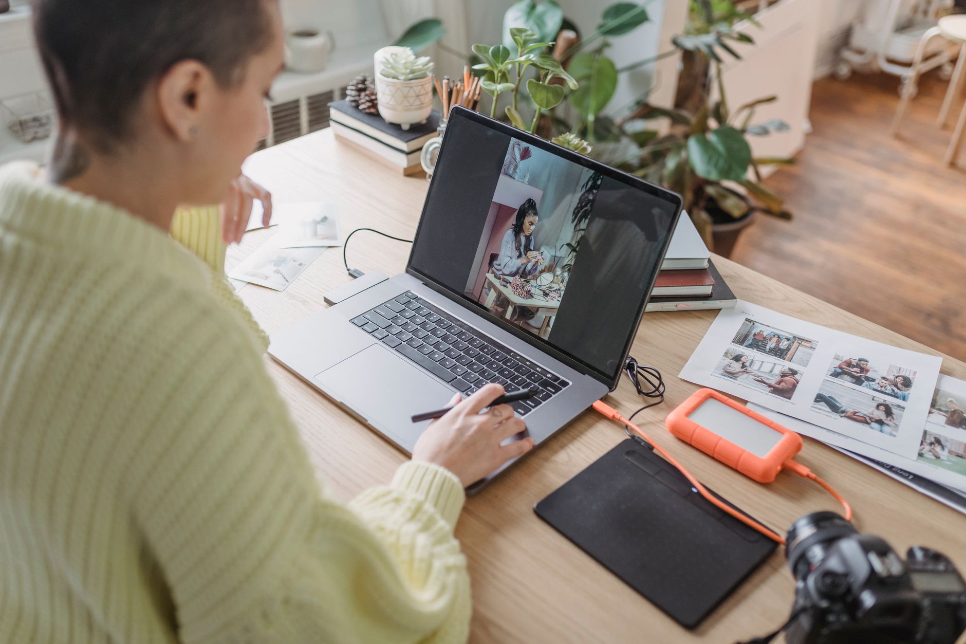 Woman editing a photo on a laptop at a desk in a bright room