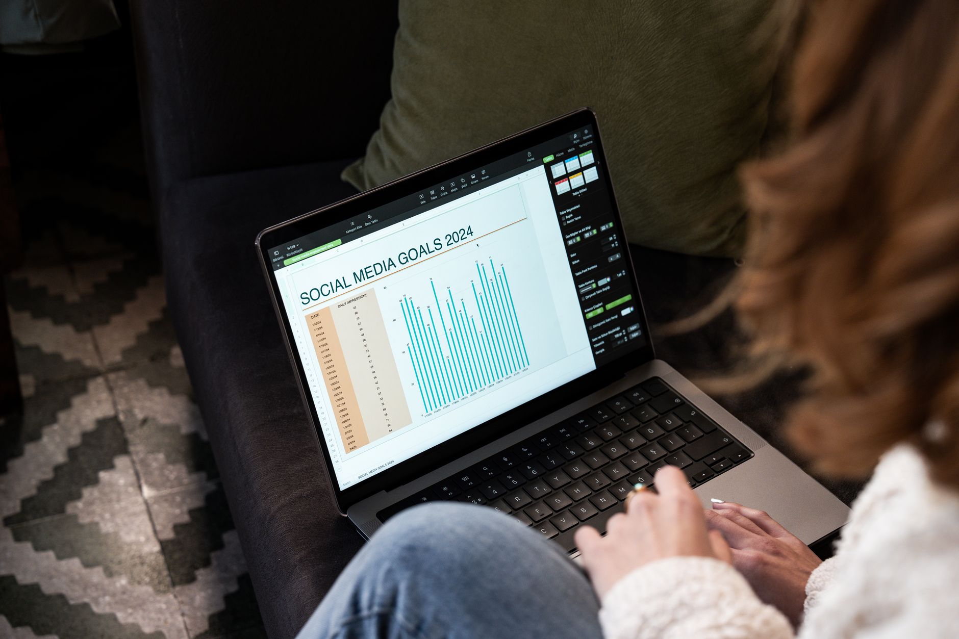 a marketer reviewing a social media content calendar on a laptop in a bright home office
