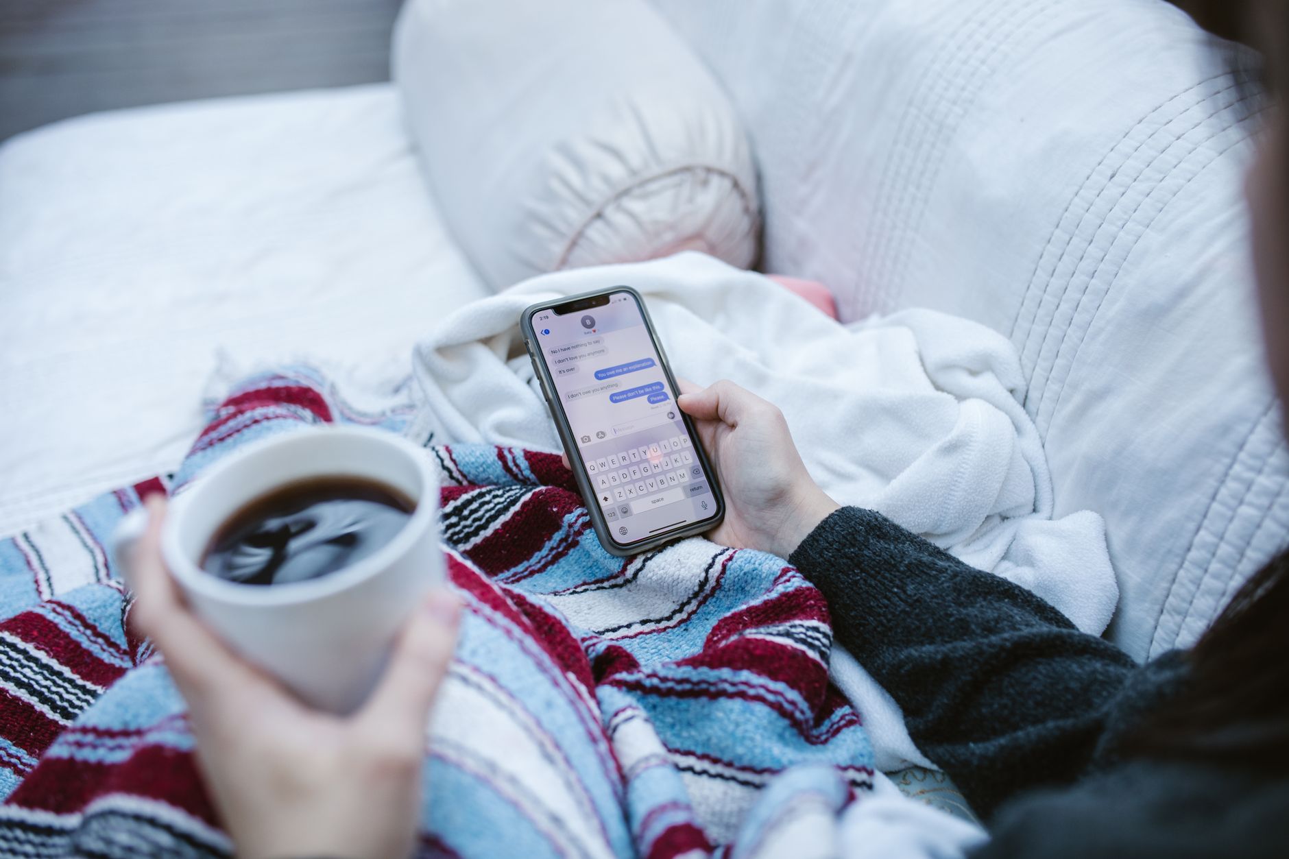 a woman using live chat on a smartphone while sitting on a couch