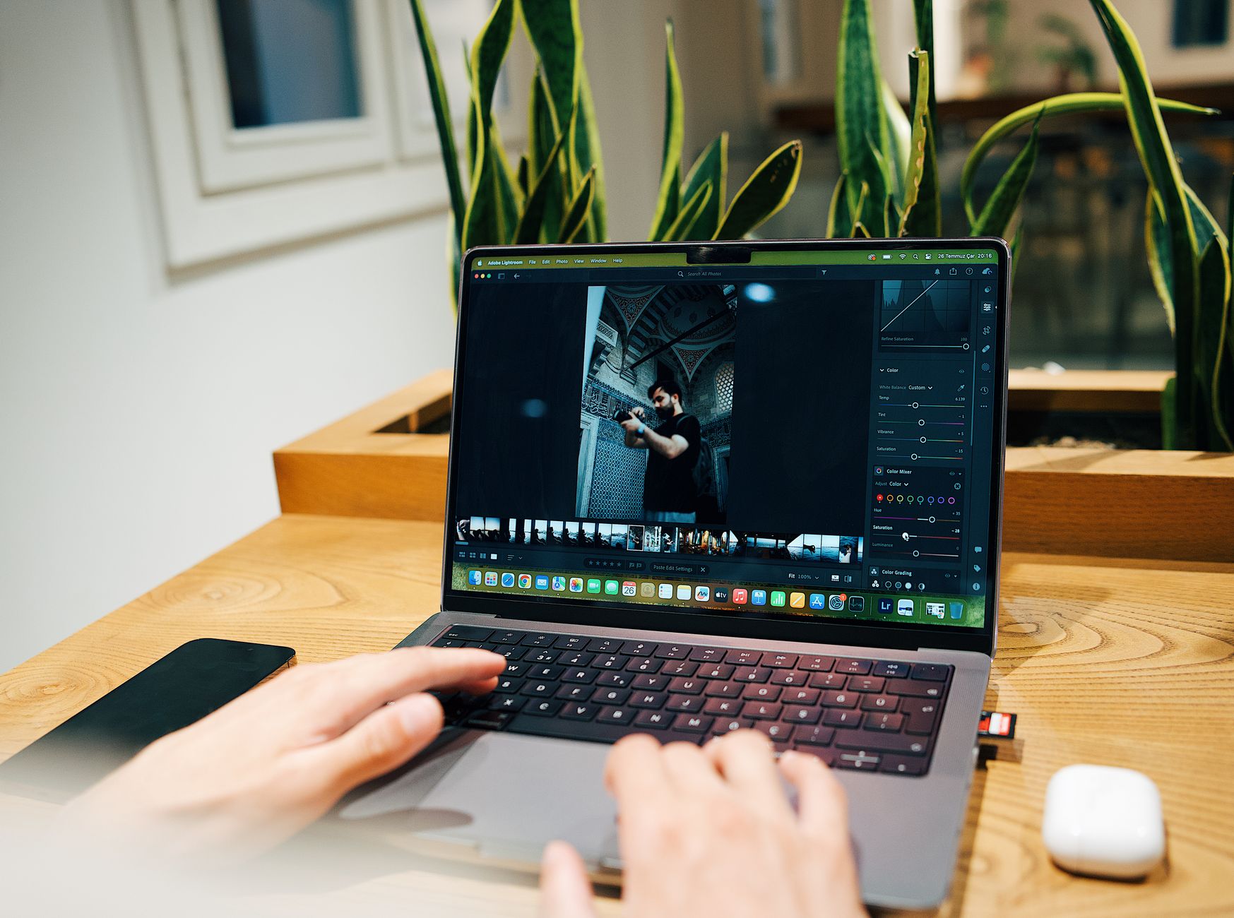 a photographer sorting a large batch of photos on a laptop in a home studio
