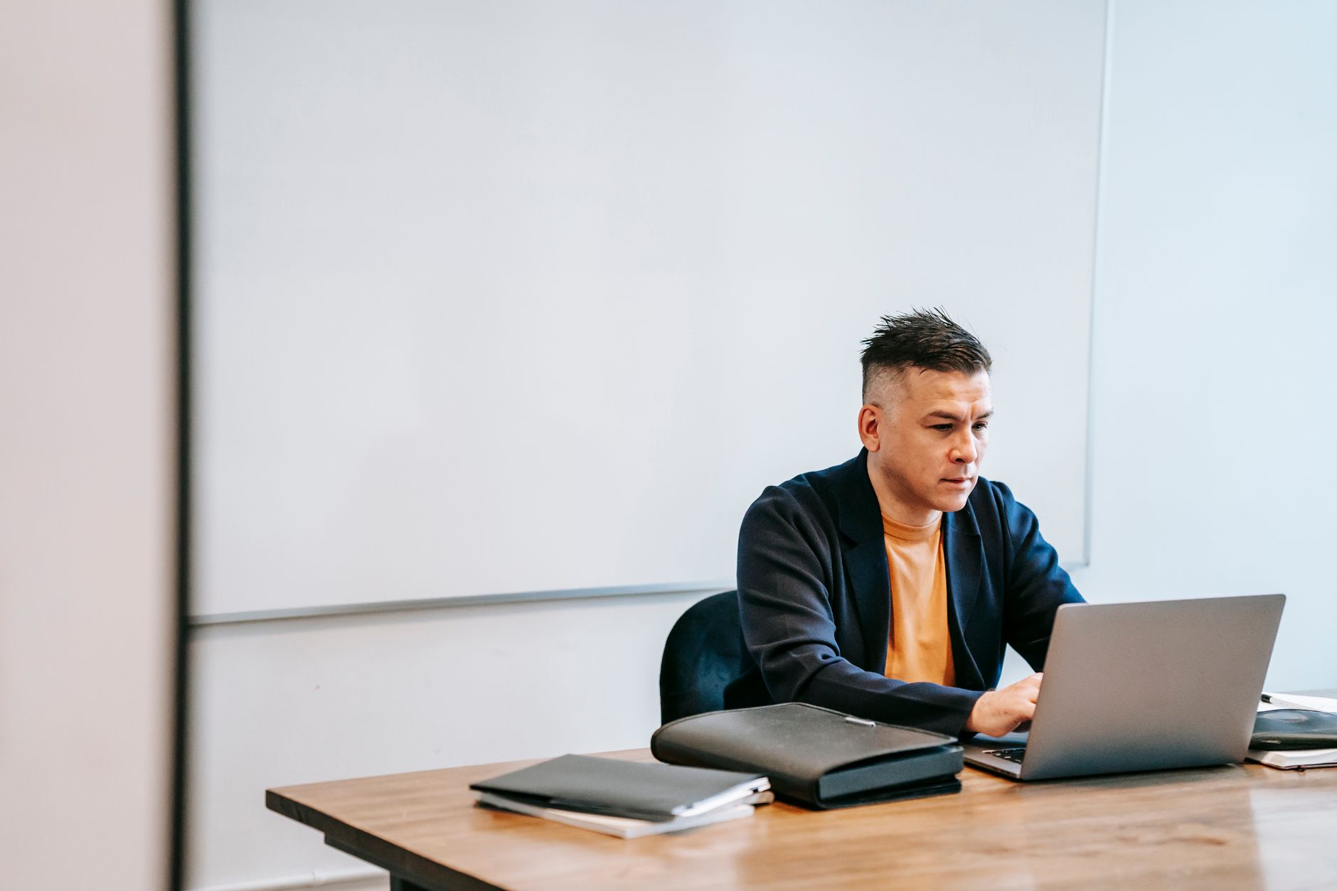 a property manager sitting at a desk in a leasing office, typing on a laptop with a property management dashboard on screen