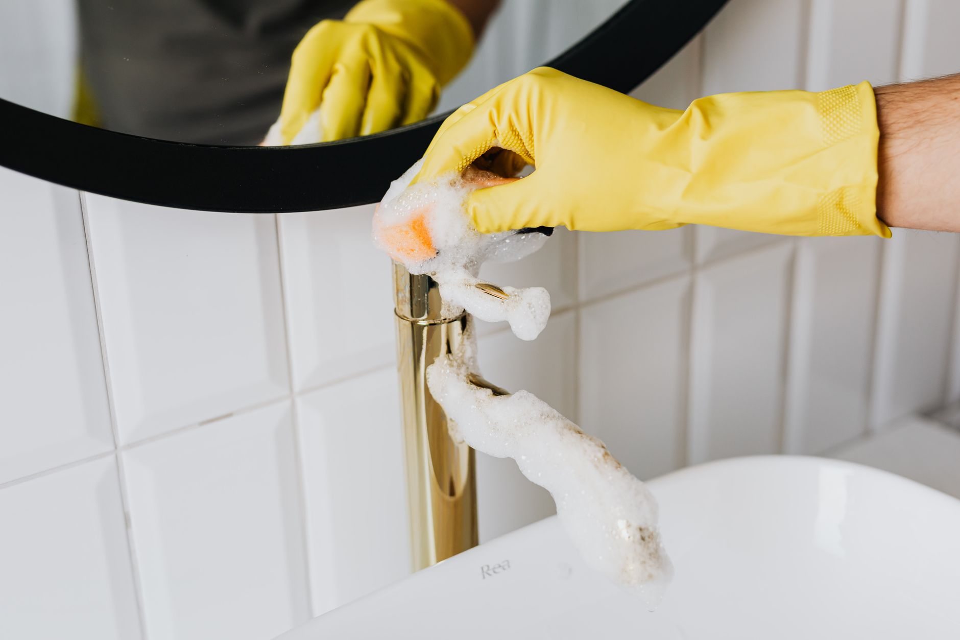 a maintenance worker taking a photo of water damage under a sink with a smartphone
