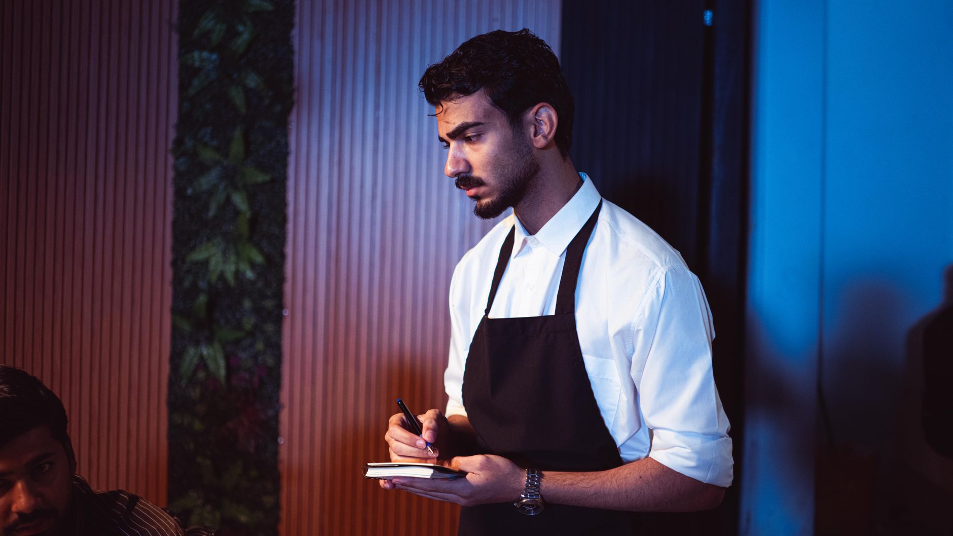 a restaurant owner holding a tablet and reviewing a digital menu in a commercial kitchen
