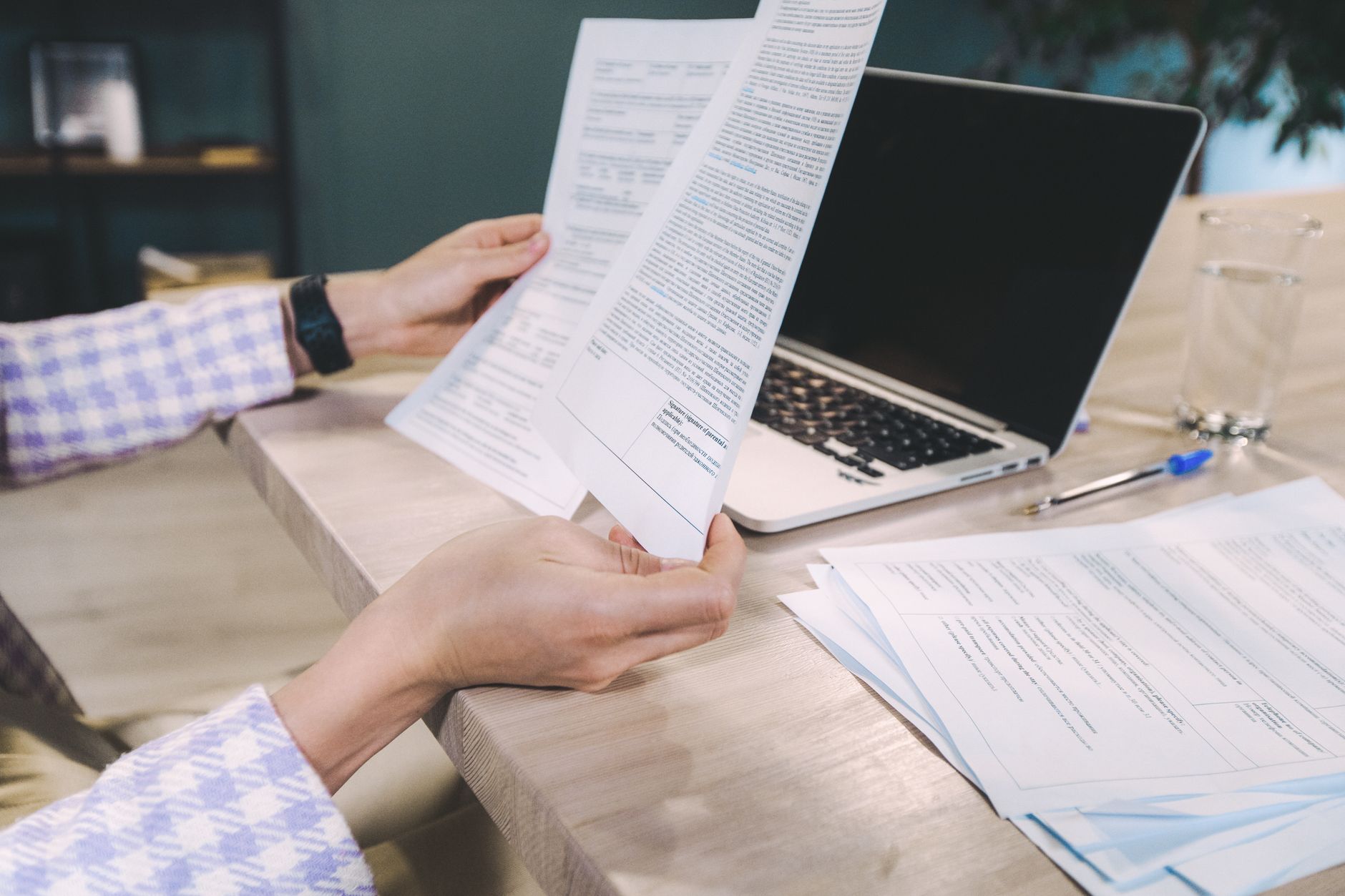a restaurant owner sitting at a table with a laptop reviewing a printed contract
