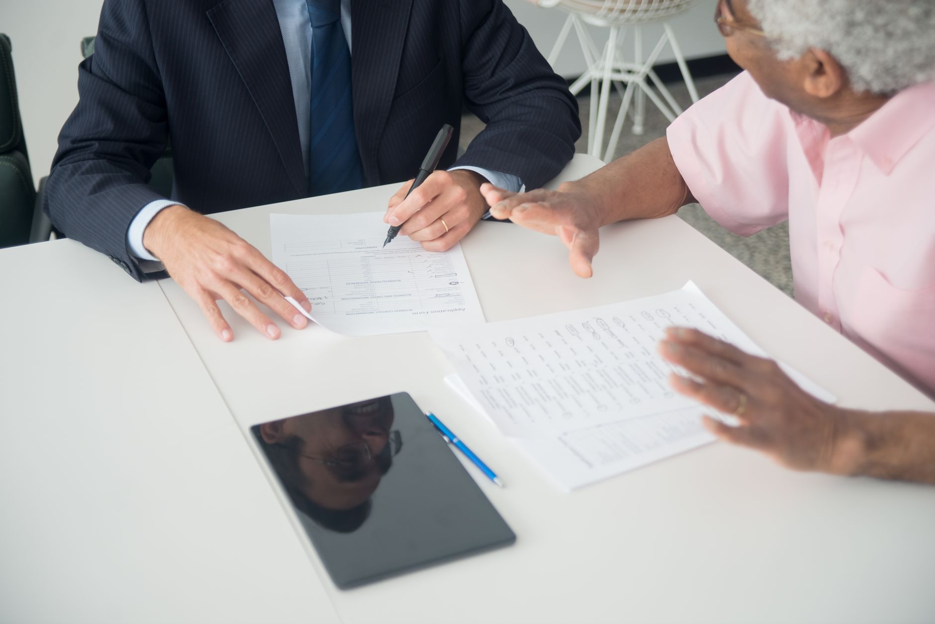 a compliance officer reviewing documents on a tablet next to a financial advisor