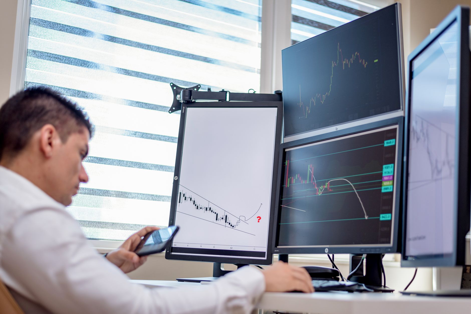 An accountant using Microsoft Excel on a large monitor with financial charts visible