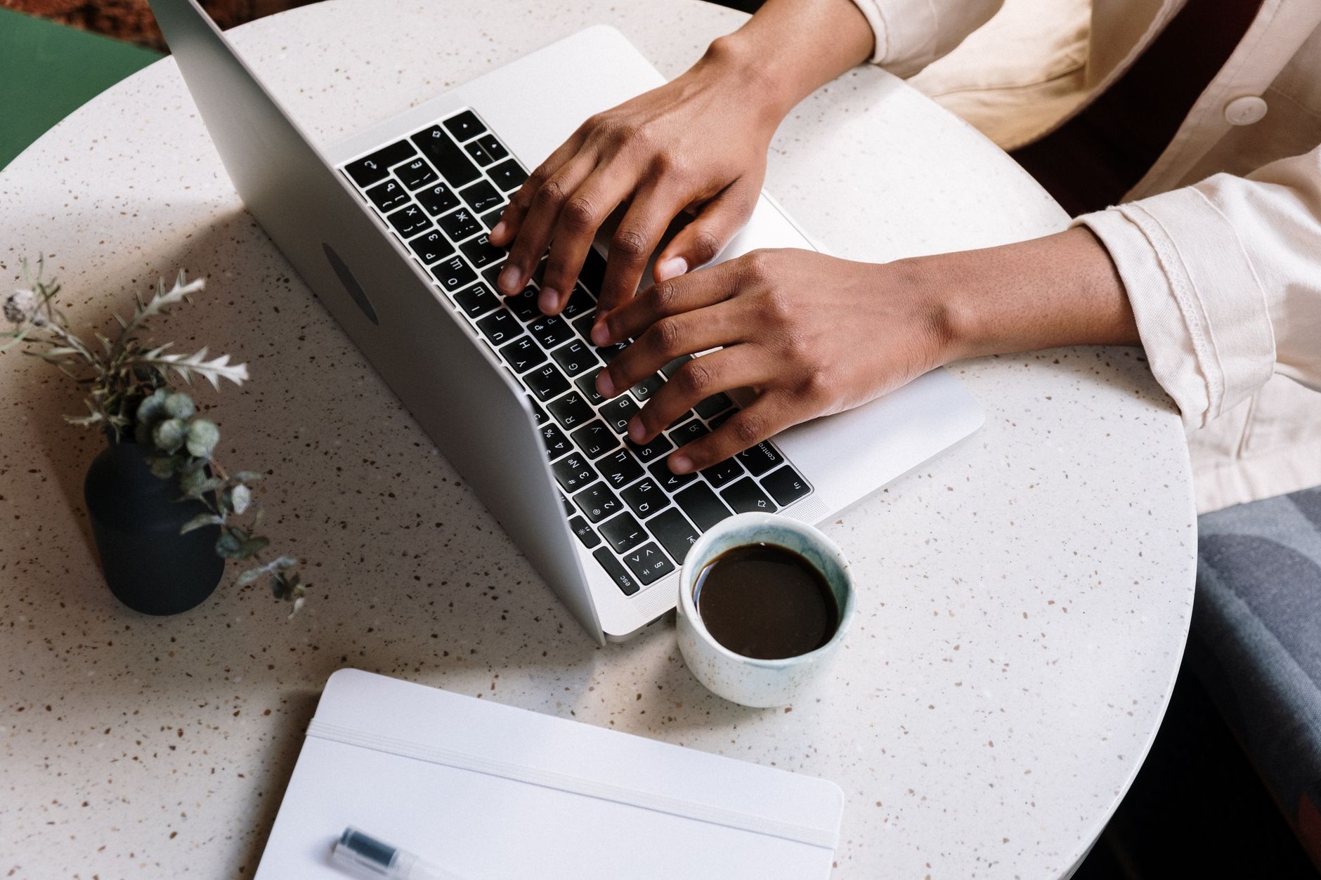 A blogger typing on a laptop at a wooden desk with a cup of coffee nearby