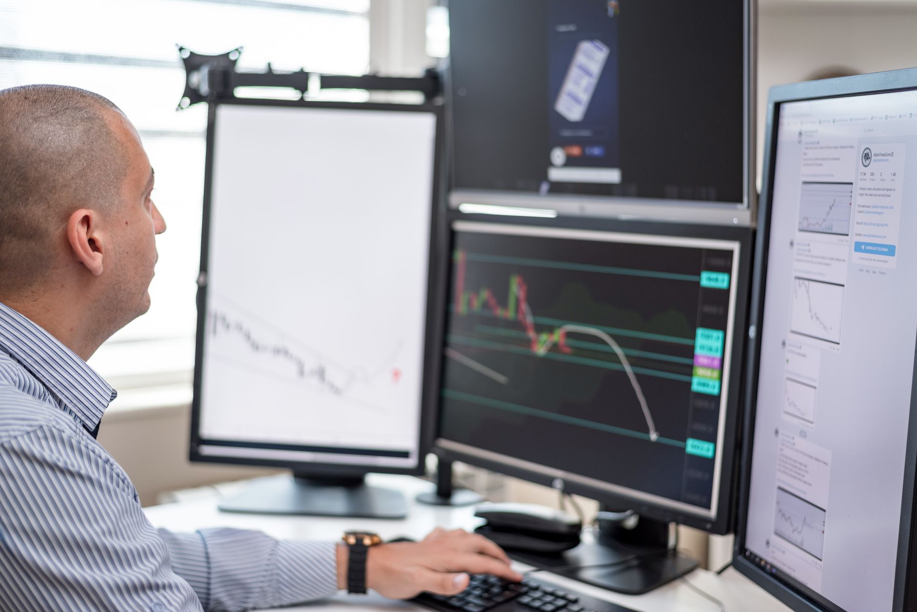 a data analyst reviewing code on a laptop while a second monitor shows charts