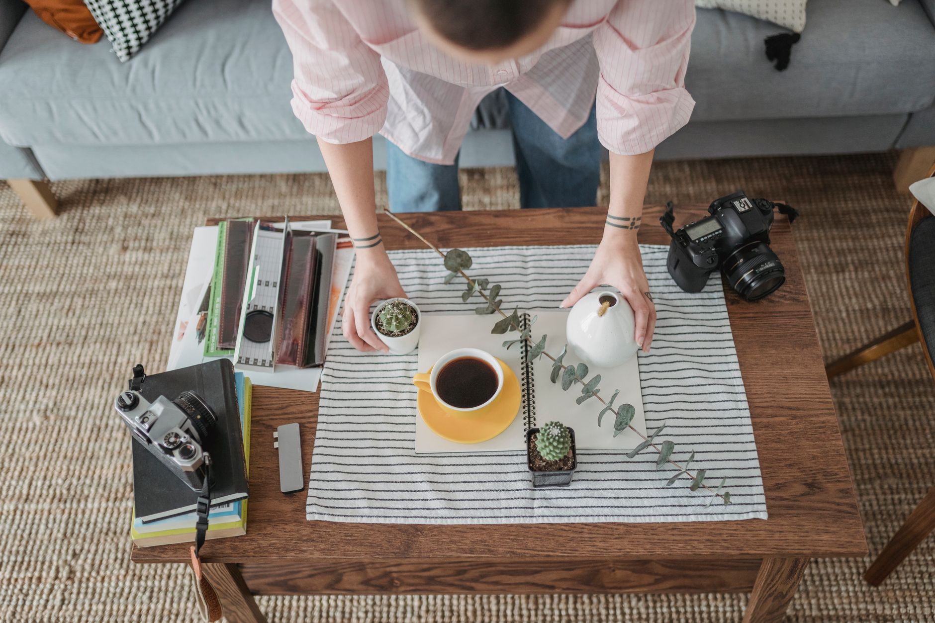 a product photographer arranging a ceramic mug on a wooden table with soft morning light