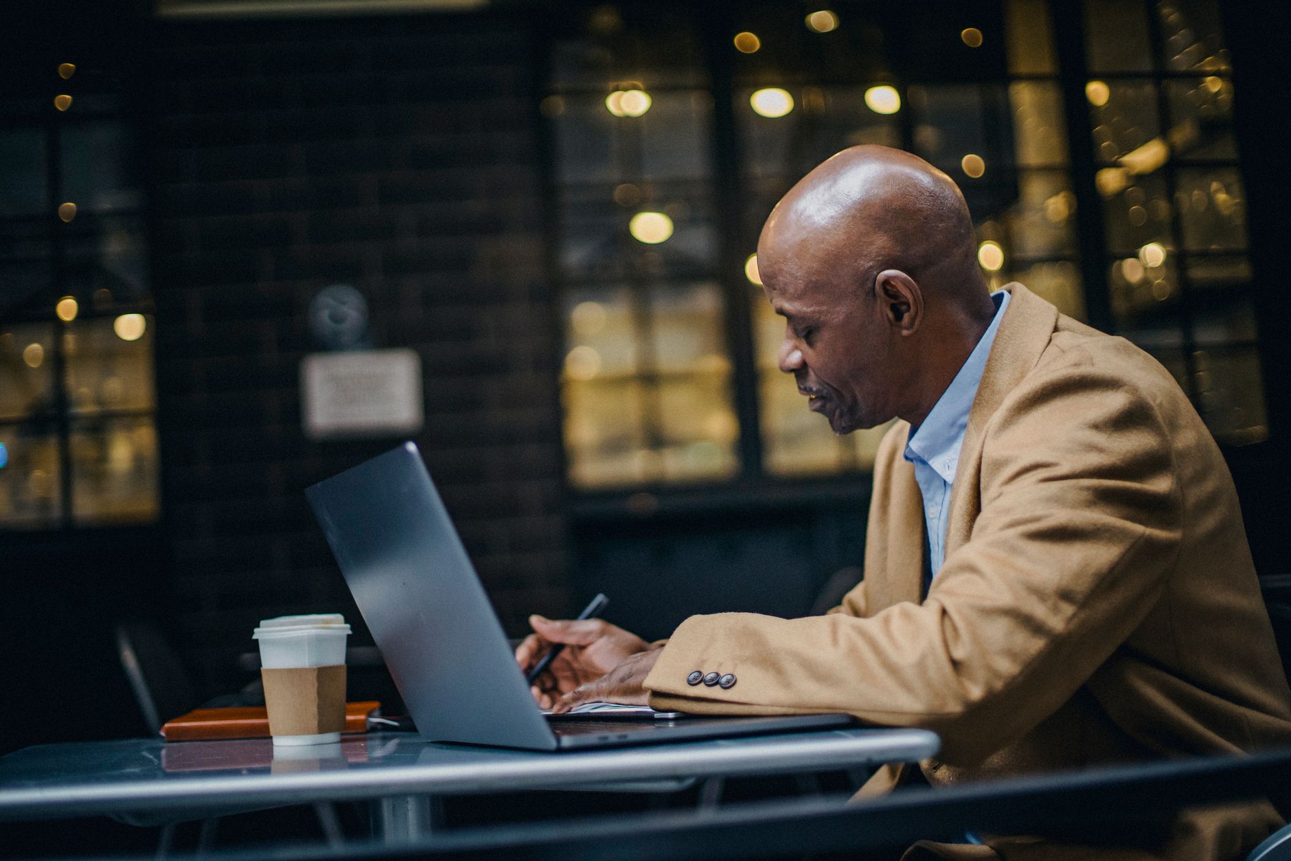 a small business owner writing an email newsletter on a laptop at a coffee shop