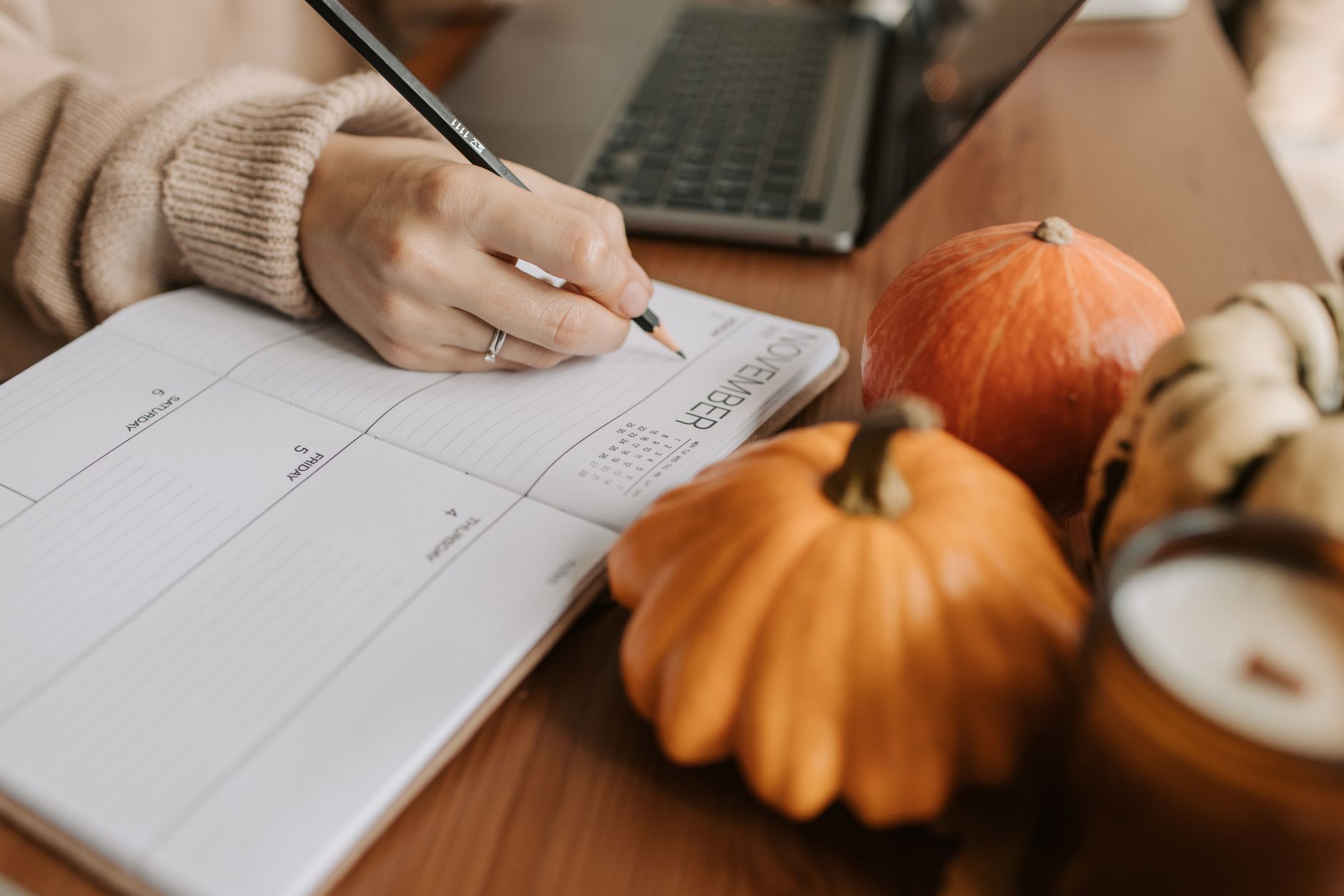 entrepreneur writing content ideas in a notebook next to a laptop