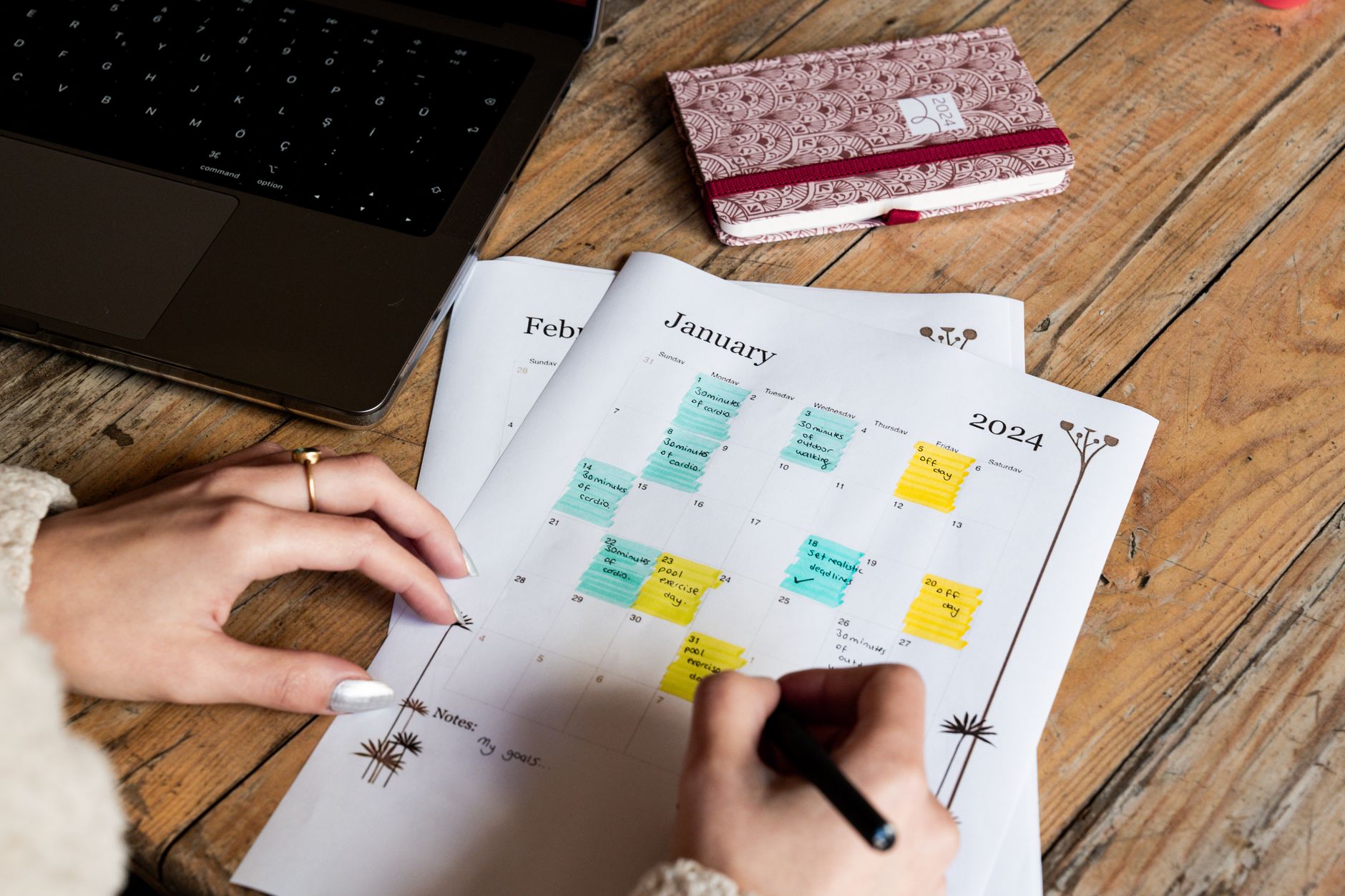 event planner writing notes at a desk with a laptop and printed checklist