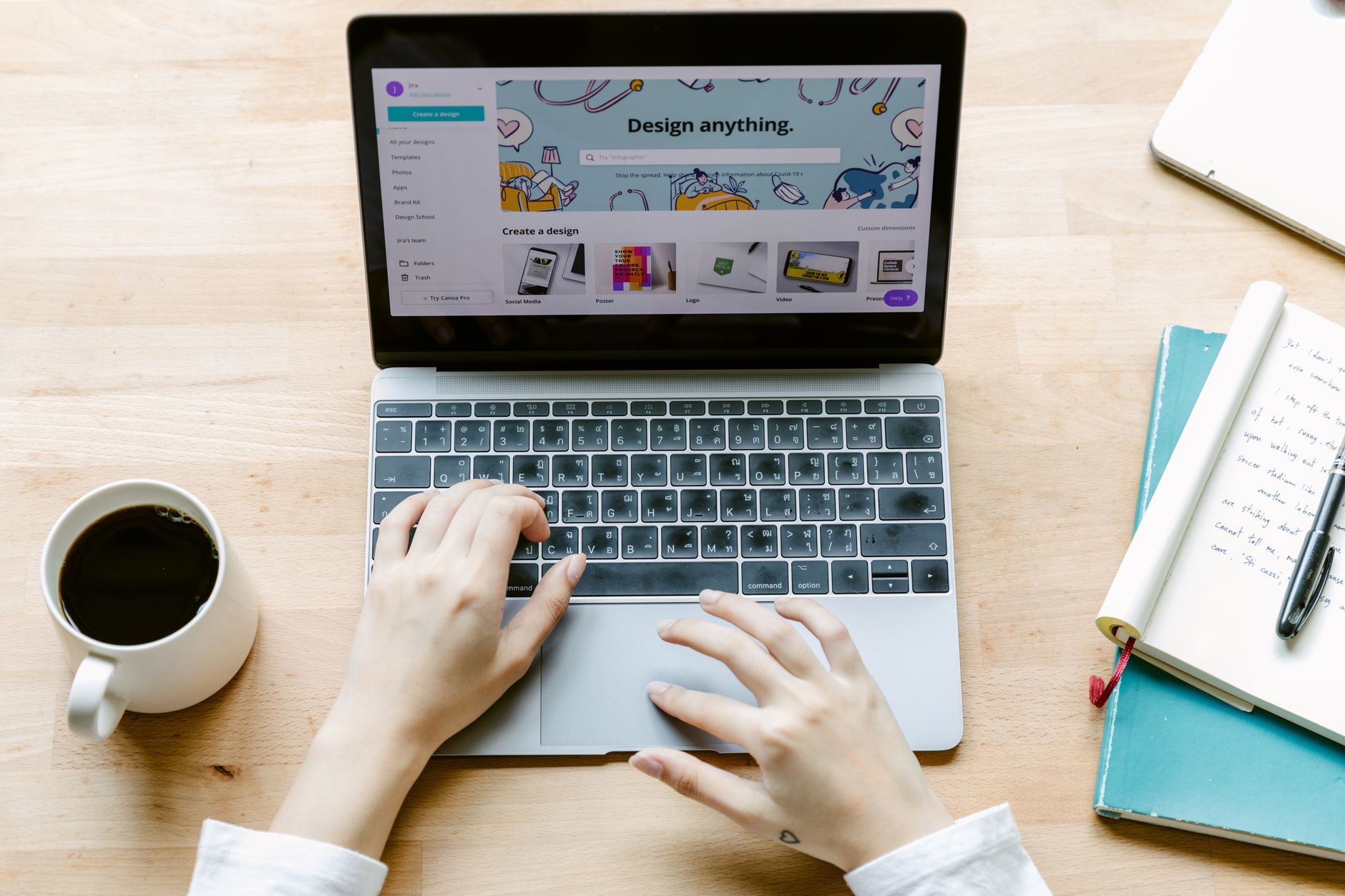 A freelancer typing on a laptop in a home office with a coffee mug on the desk.