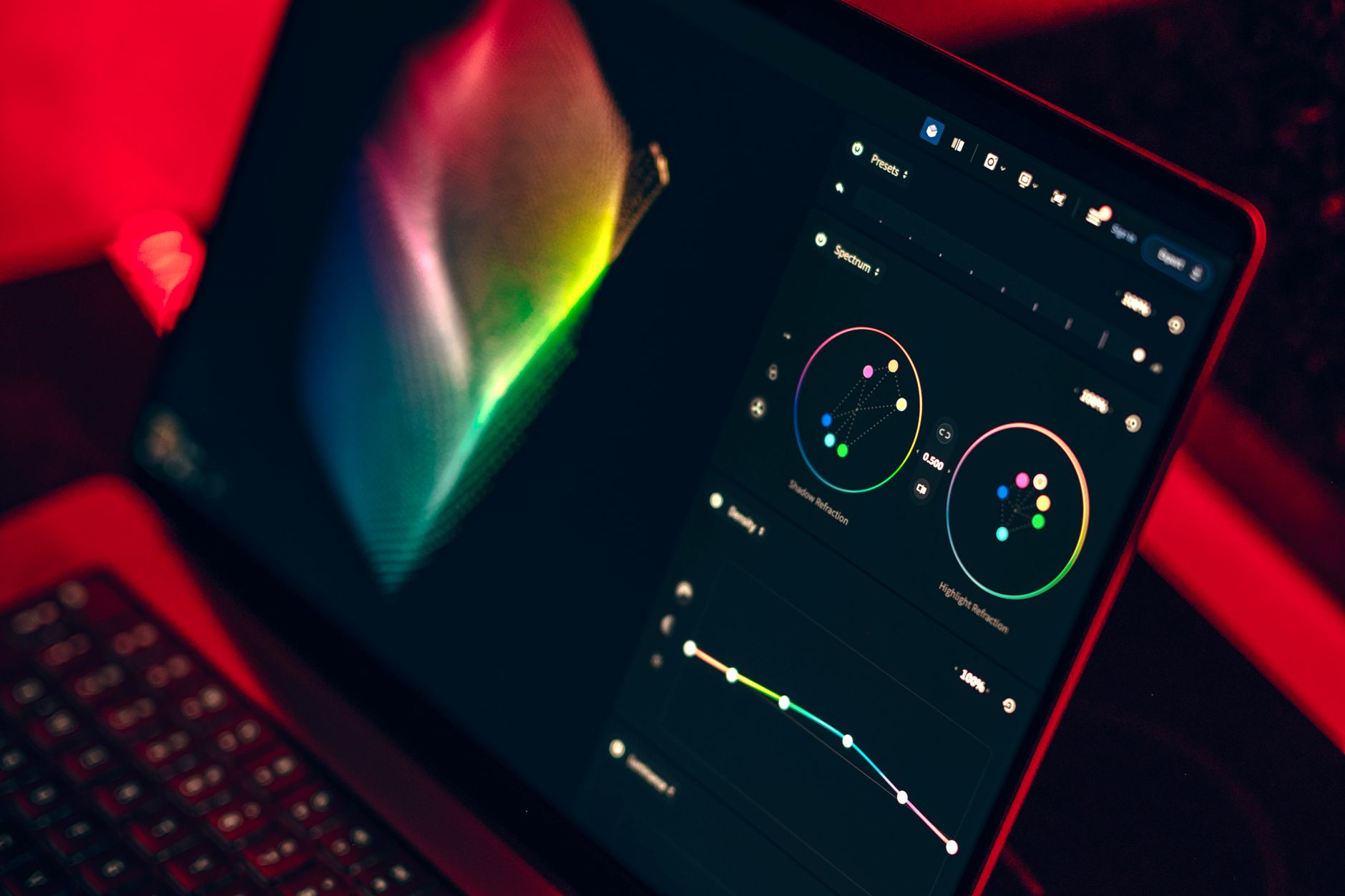 A graphic designer editing a colorful social media graphic on a laptop with a stylus in hand.