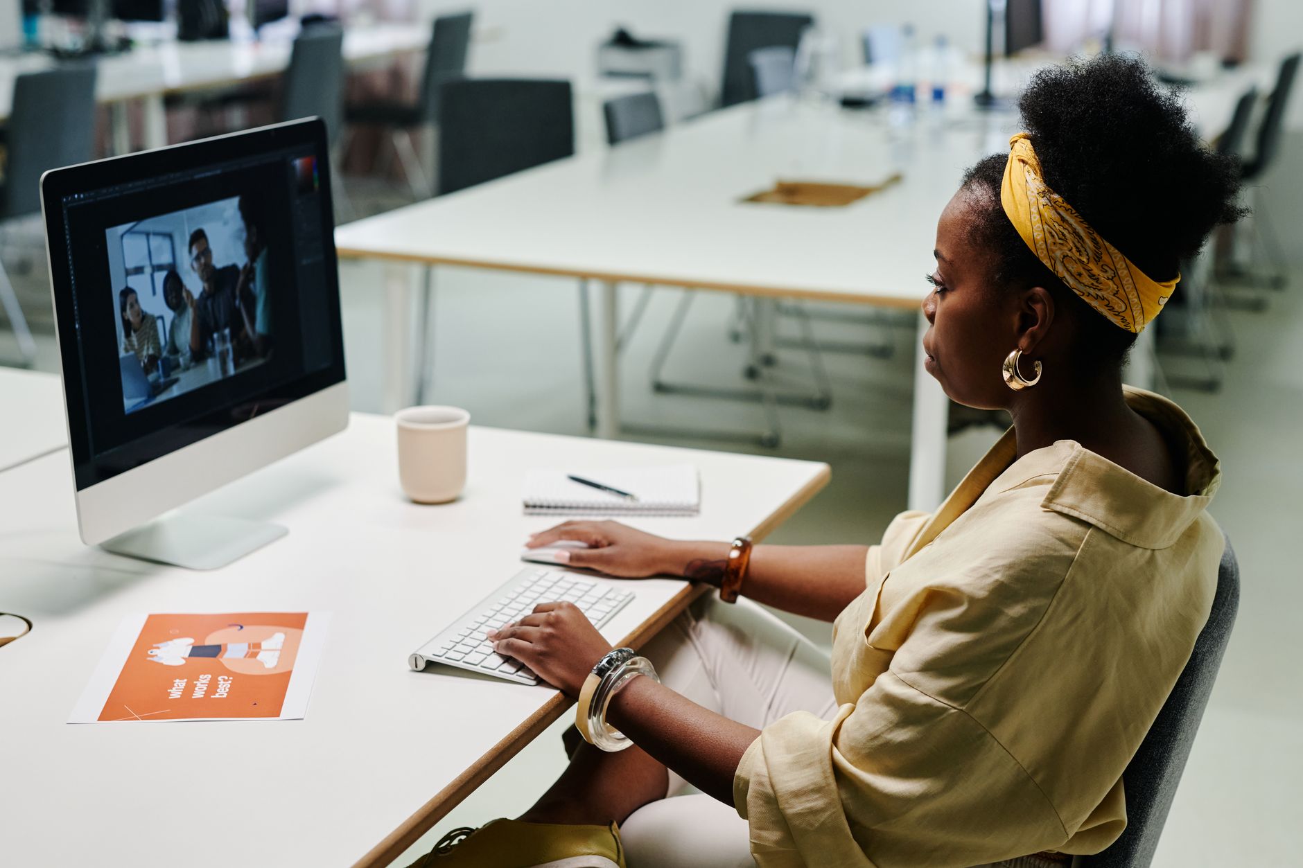 a woman using a laptop to design social media graphics with colorful templates on the screen