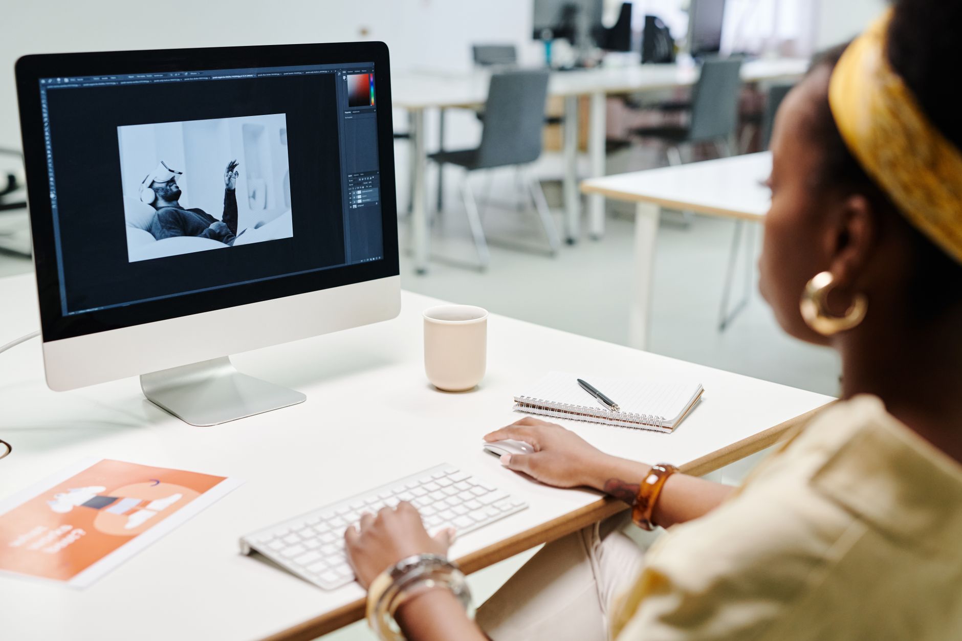 a graphic designer editing a photo in Photoshop on a desktop computer