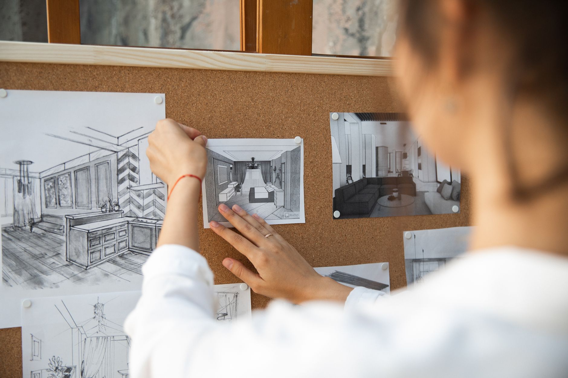 An interior designer holds a tablet showing a color mood board in a bright design studio.