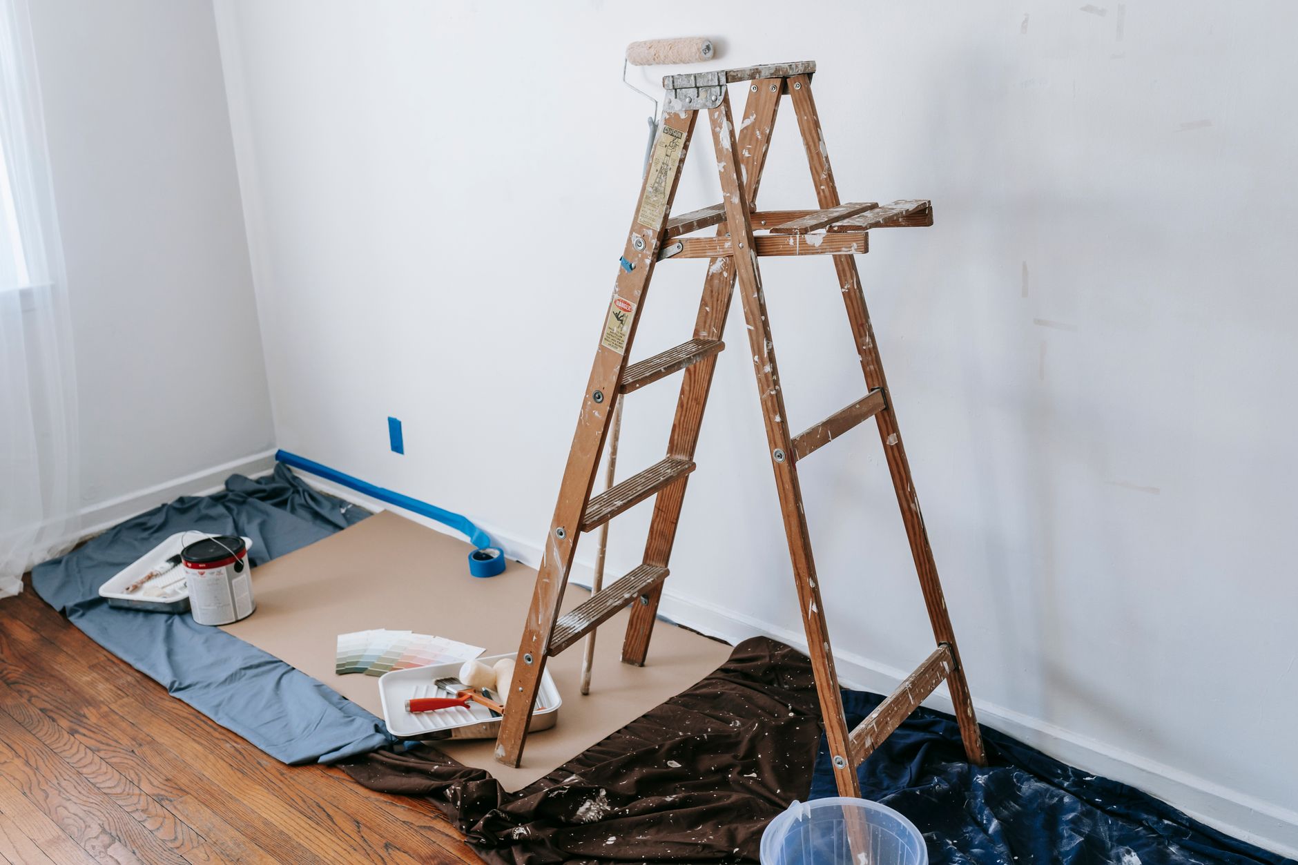 An empty room being renovated, with paint swatches on the wall and a step ladder in the center.