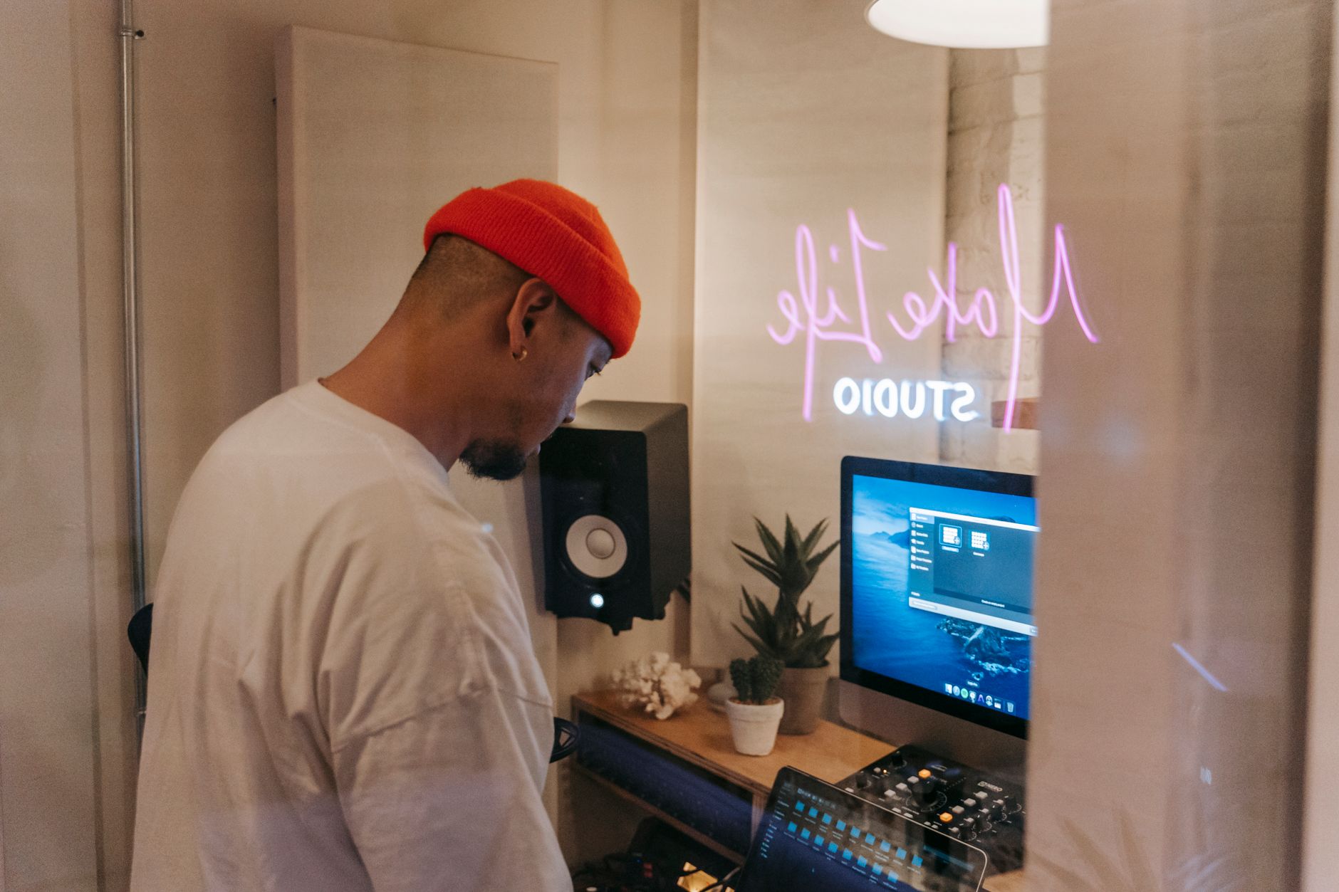 a music producer in a home studio uploading a track on a laptop with studio monitors