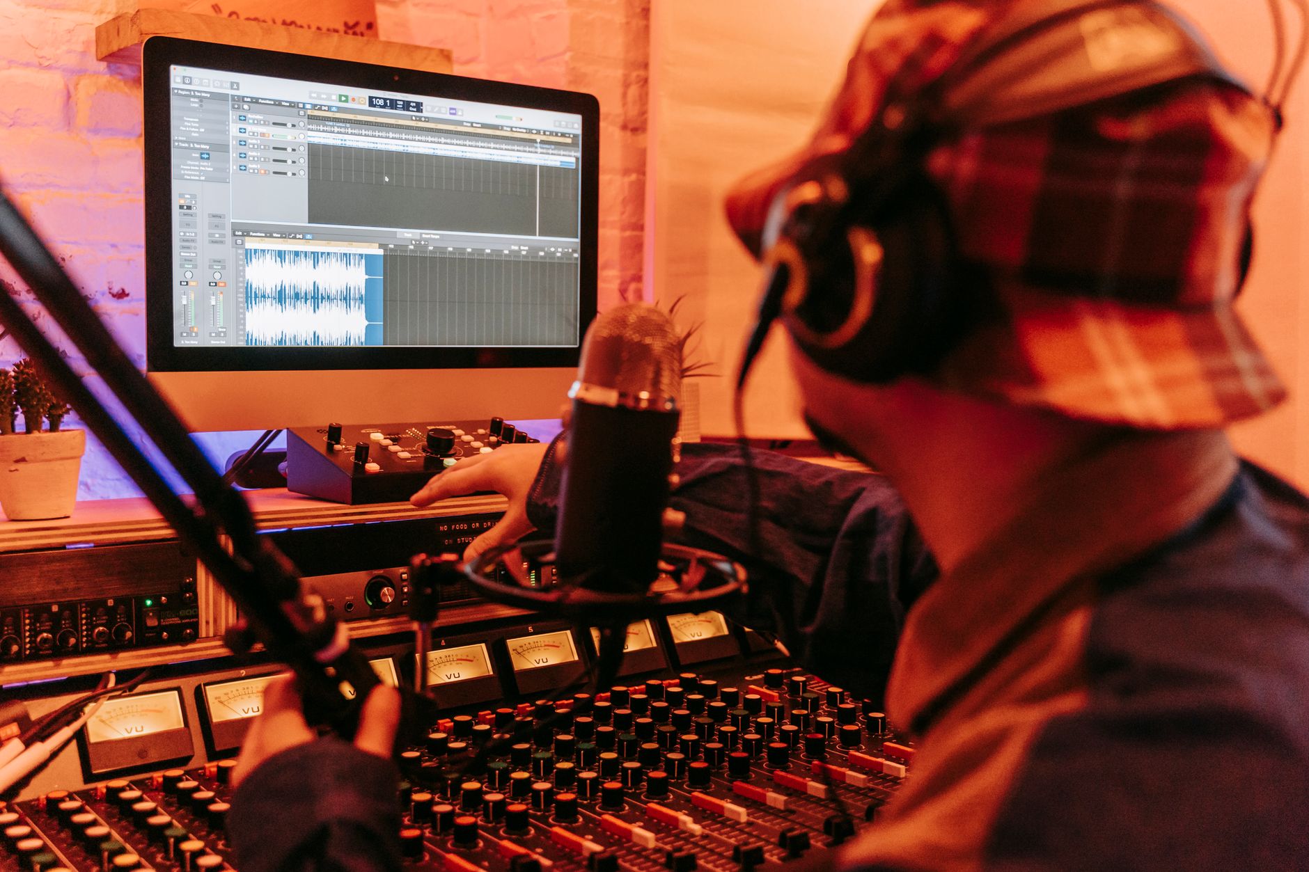 a music producer listening to stems on a laptop while wearing headphones