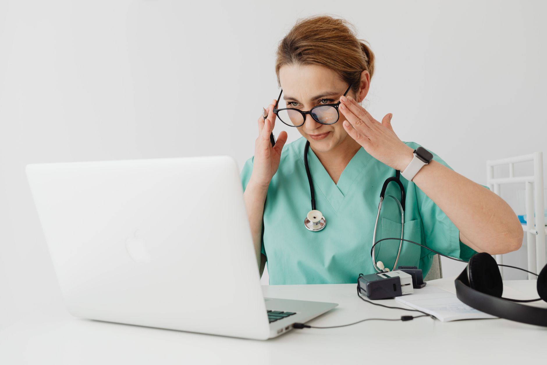a nurse in scrubs looking at a scheduling calendar on a computer screen in an office
