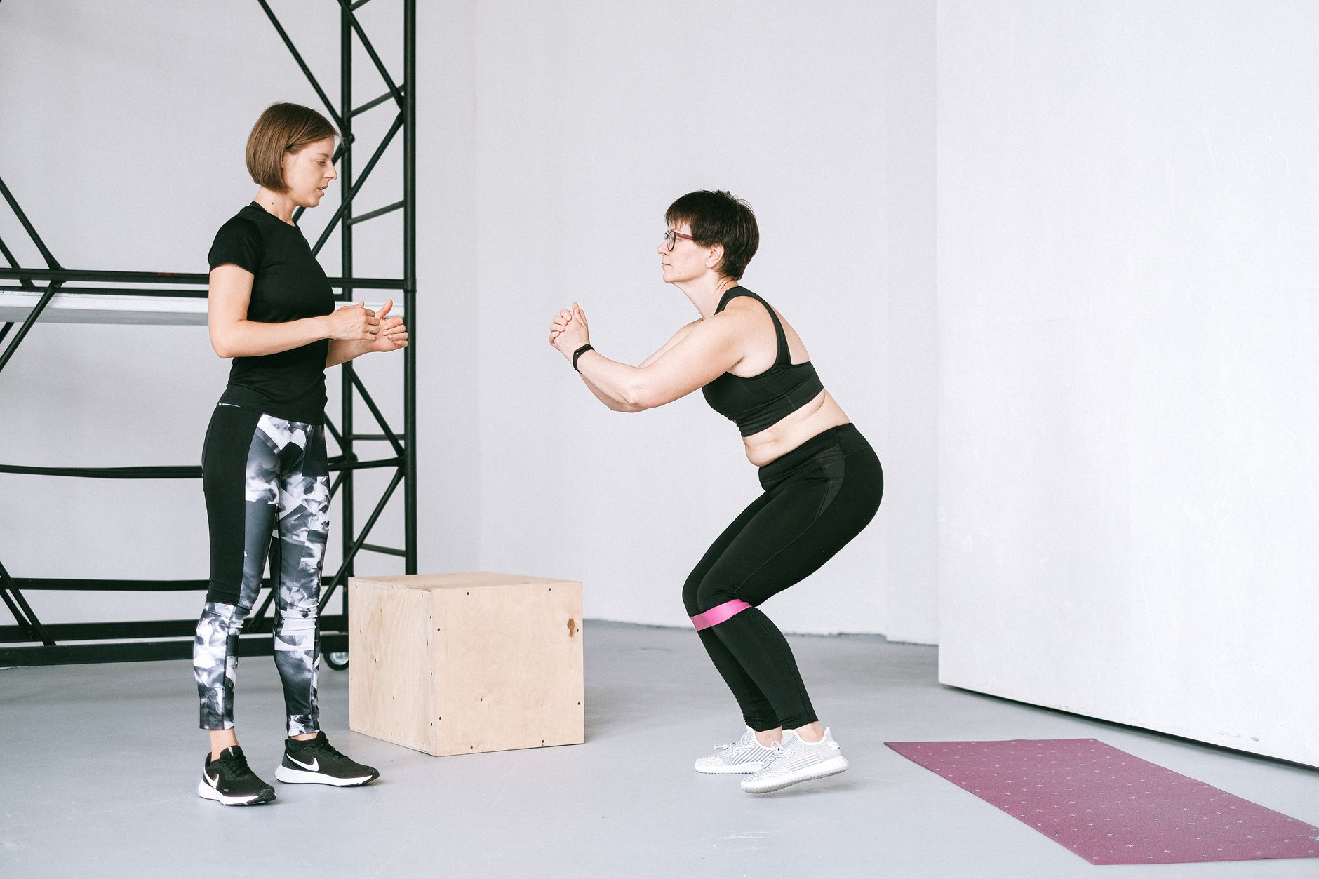 personal trainer recording a client squat form with a smartphone in a gym