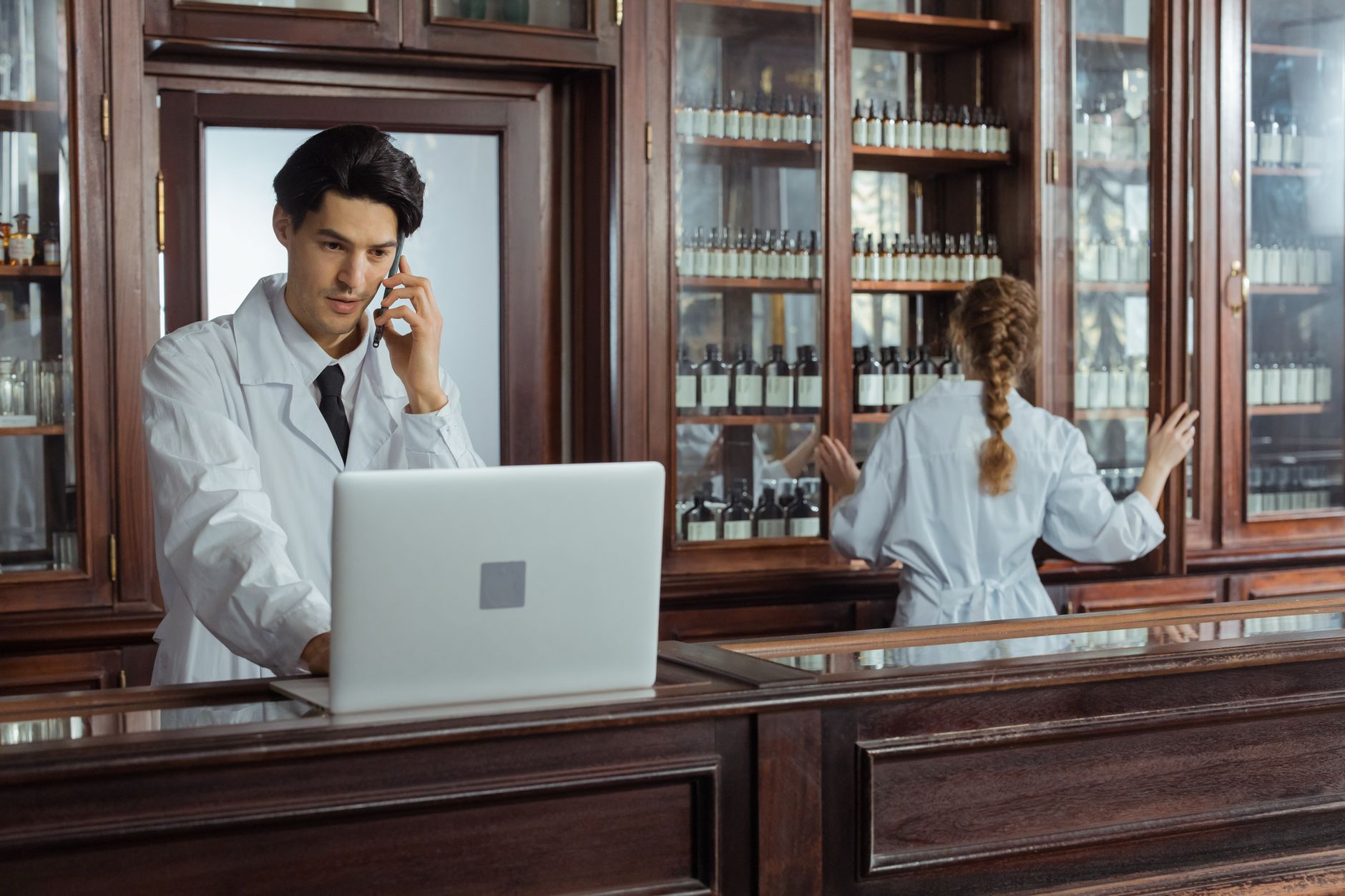 a pharmacist typing on a laptop while reviewing prescription notes