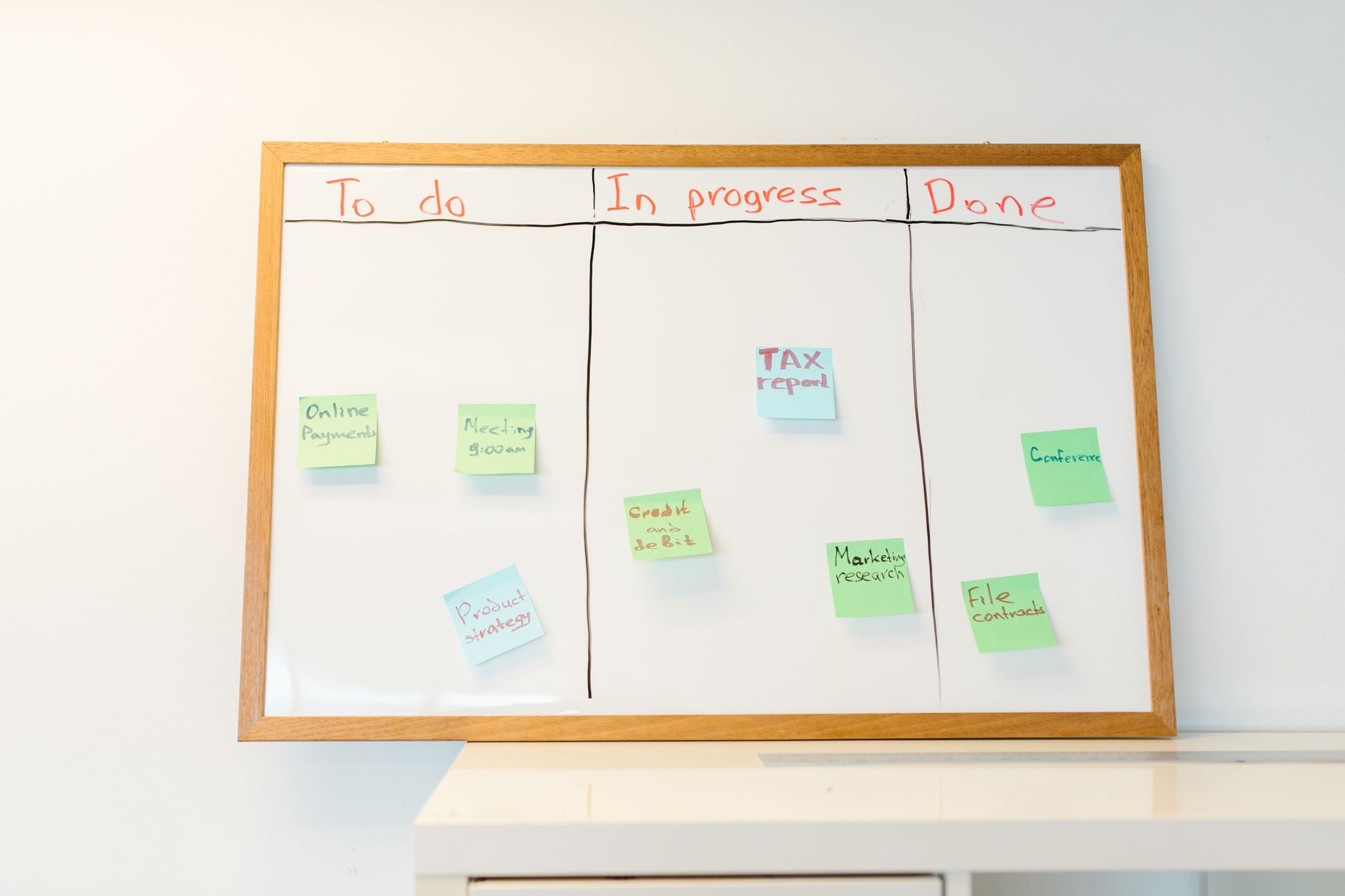 a person organizing sticky notes on a kanban board while a laptop shows Notion on screen