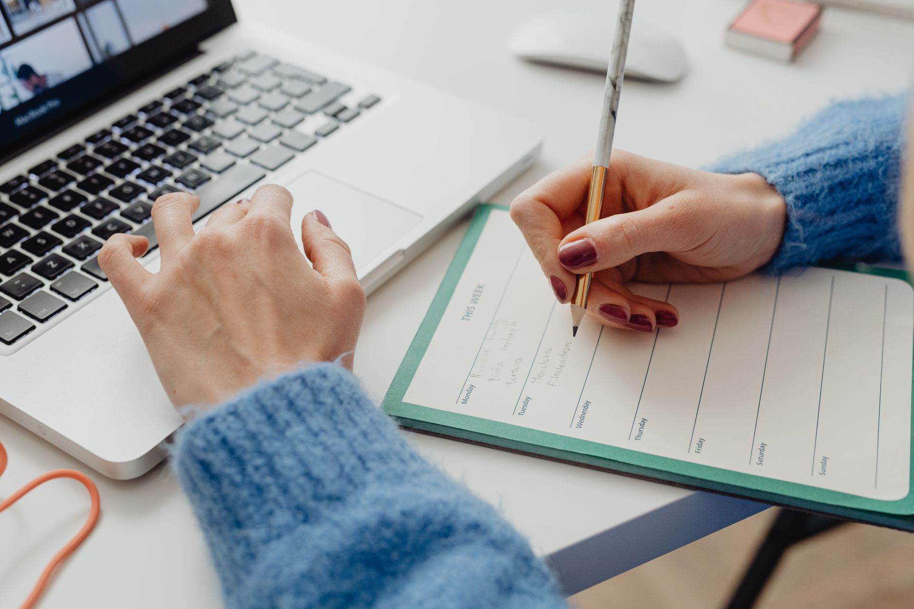 a person looking at a calendar app on a laptop while a task list sits beside them