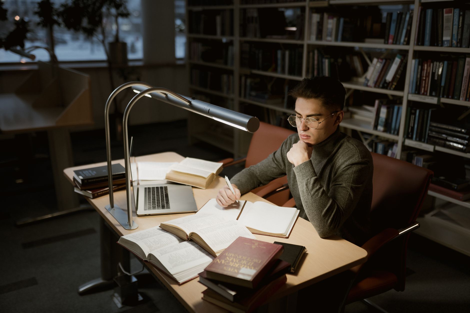 a person searching academic papers on a laptop in a library