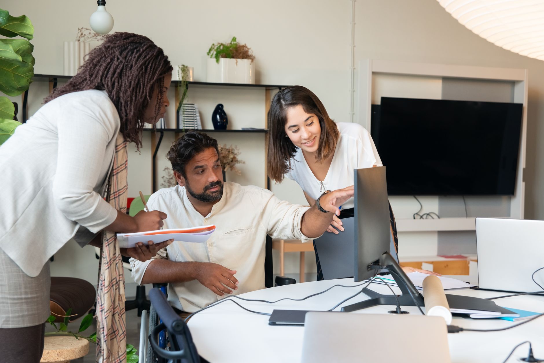 A team of three people looking at a shared calendar on a large monitor in a meeting room