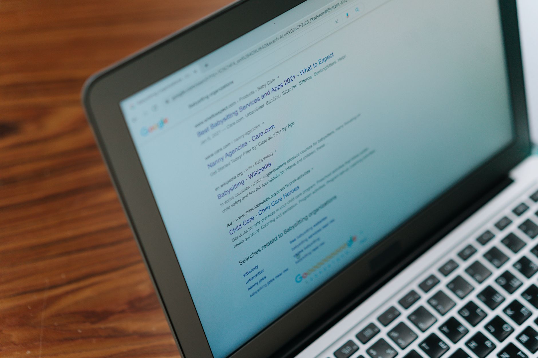 a person checking search results on a laptop with a notebook beside them