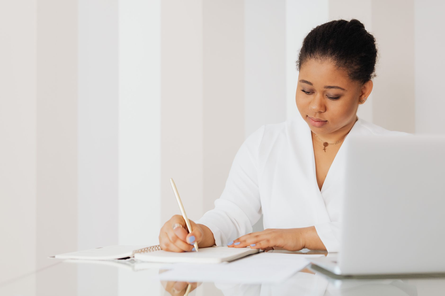 a therapist typing progress notes on a laptop in a calm office with a notebook beside them