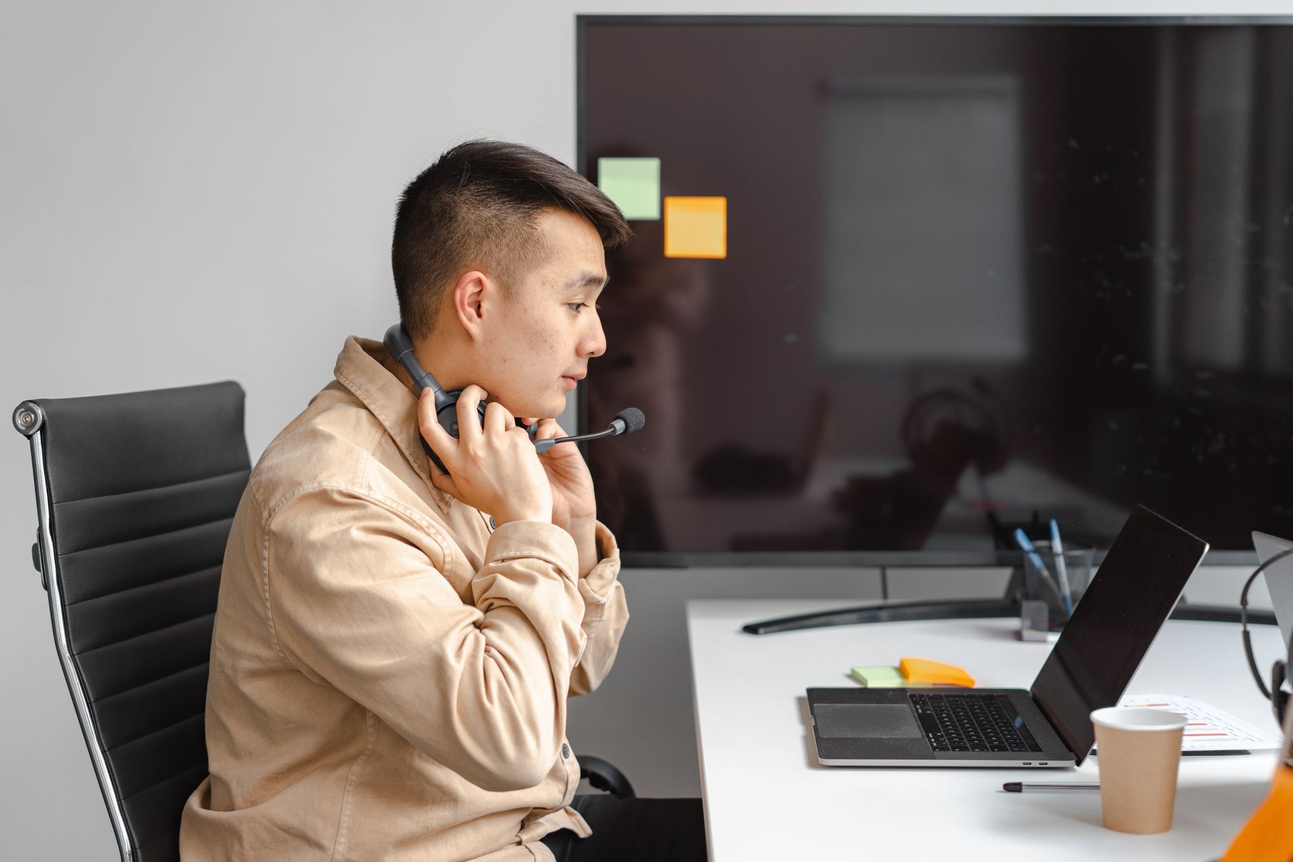 a businessperson taking notes during a video call on a laptop