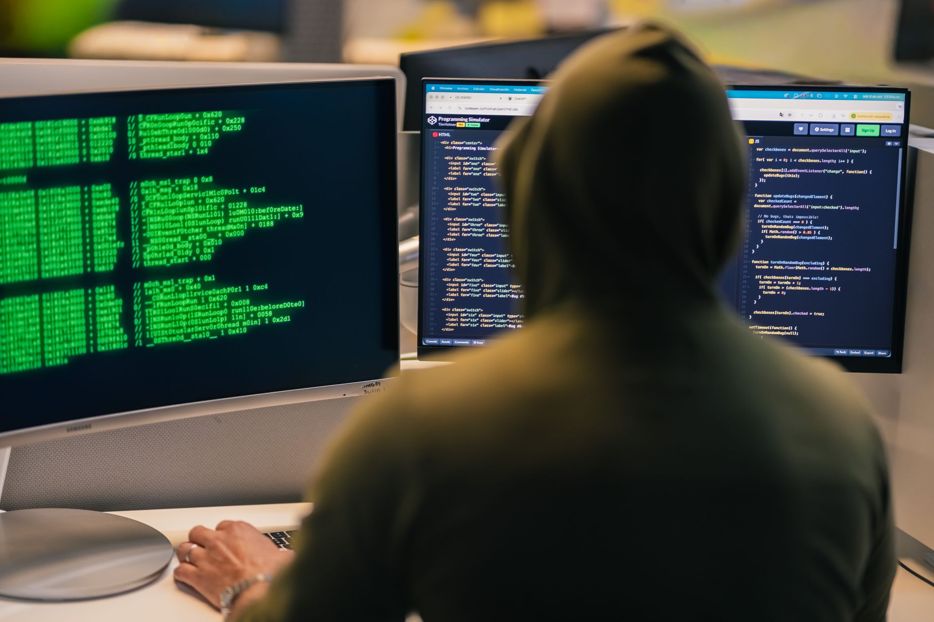 a developer reviewing code changes on a dual monitor setup in an office