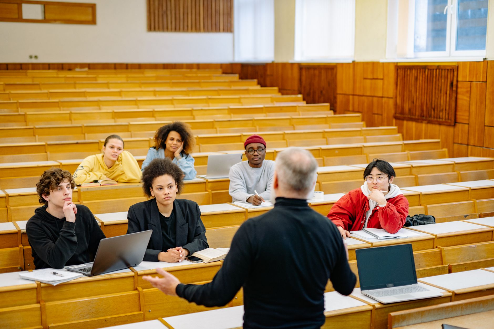 a student typing notes on a laptop during a lecture in a university lecture hall