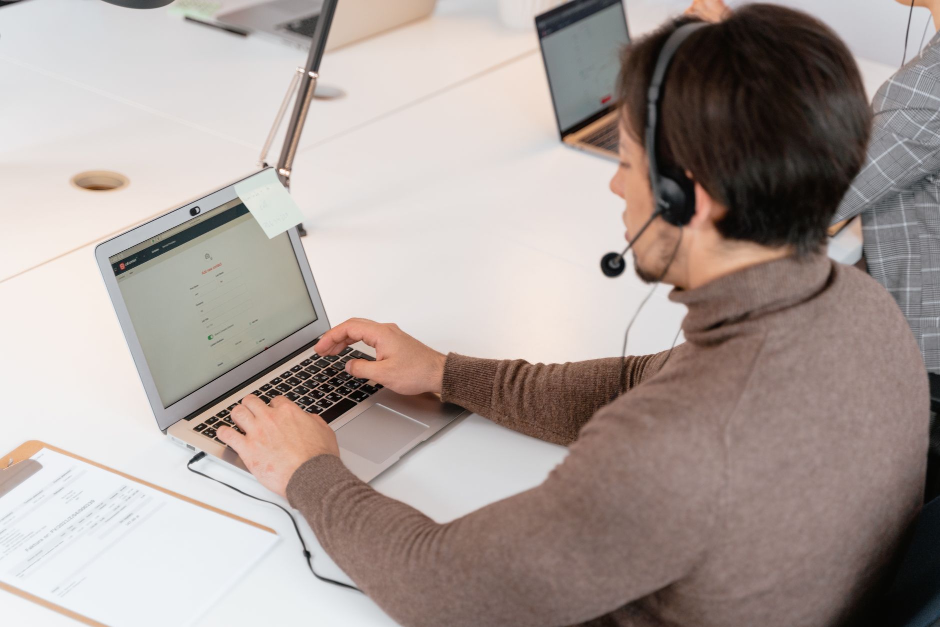 a customer service representative typing on a computer while wearing a headset