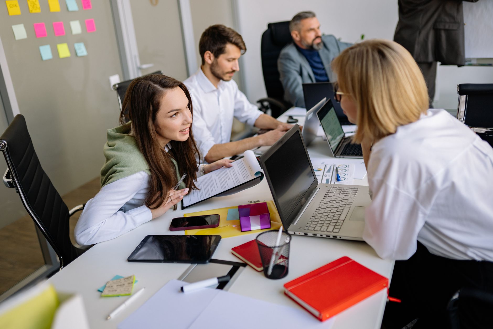 a marketing professional planning content on a laptop with sticky notes on the wall