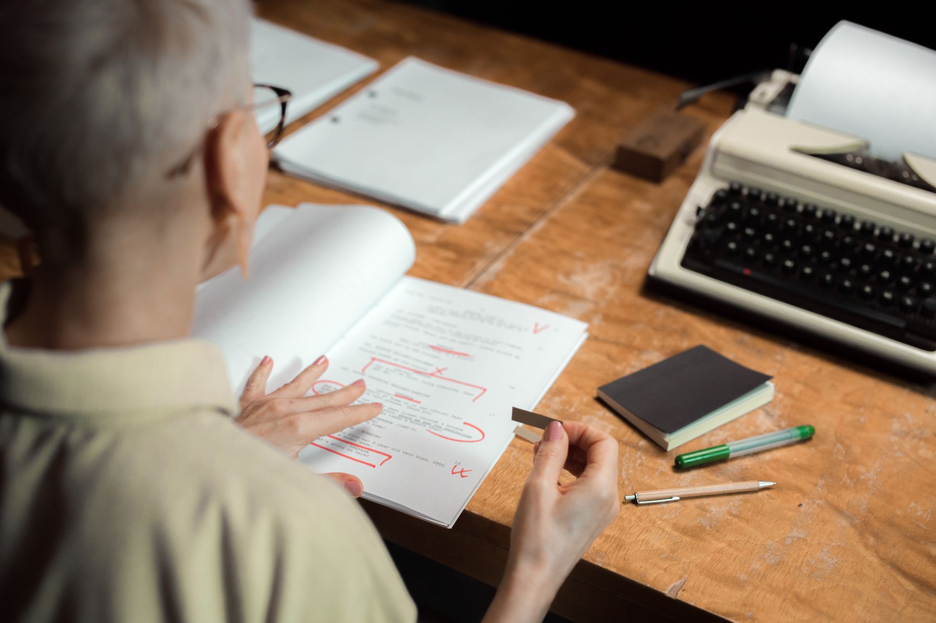 a person reviewing a printed document with a red pen at a desk