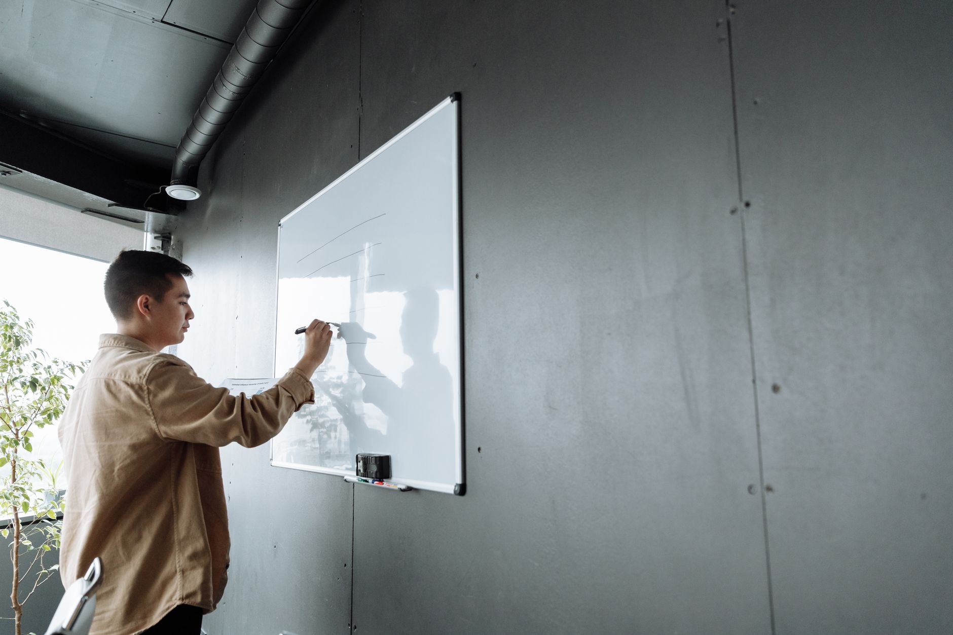 A business person writing process steps on a whiteboard in a modern office