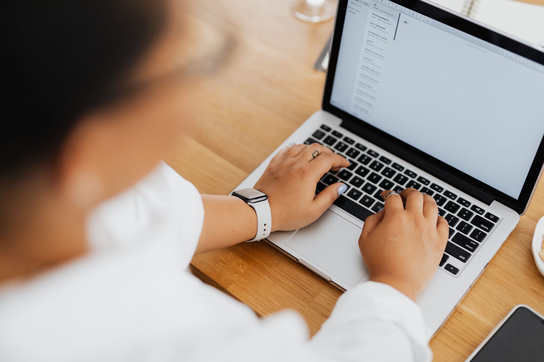 Founder typing cold email copy on laptop at coffee shop desk