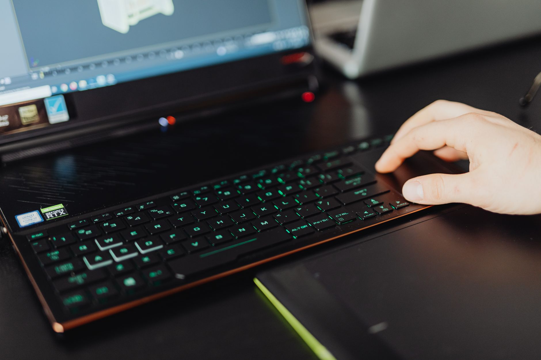 A person adjusts a colorful 3D model of a cartoon character on a laptop screen