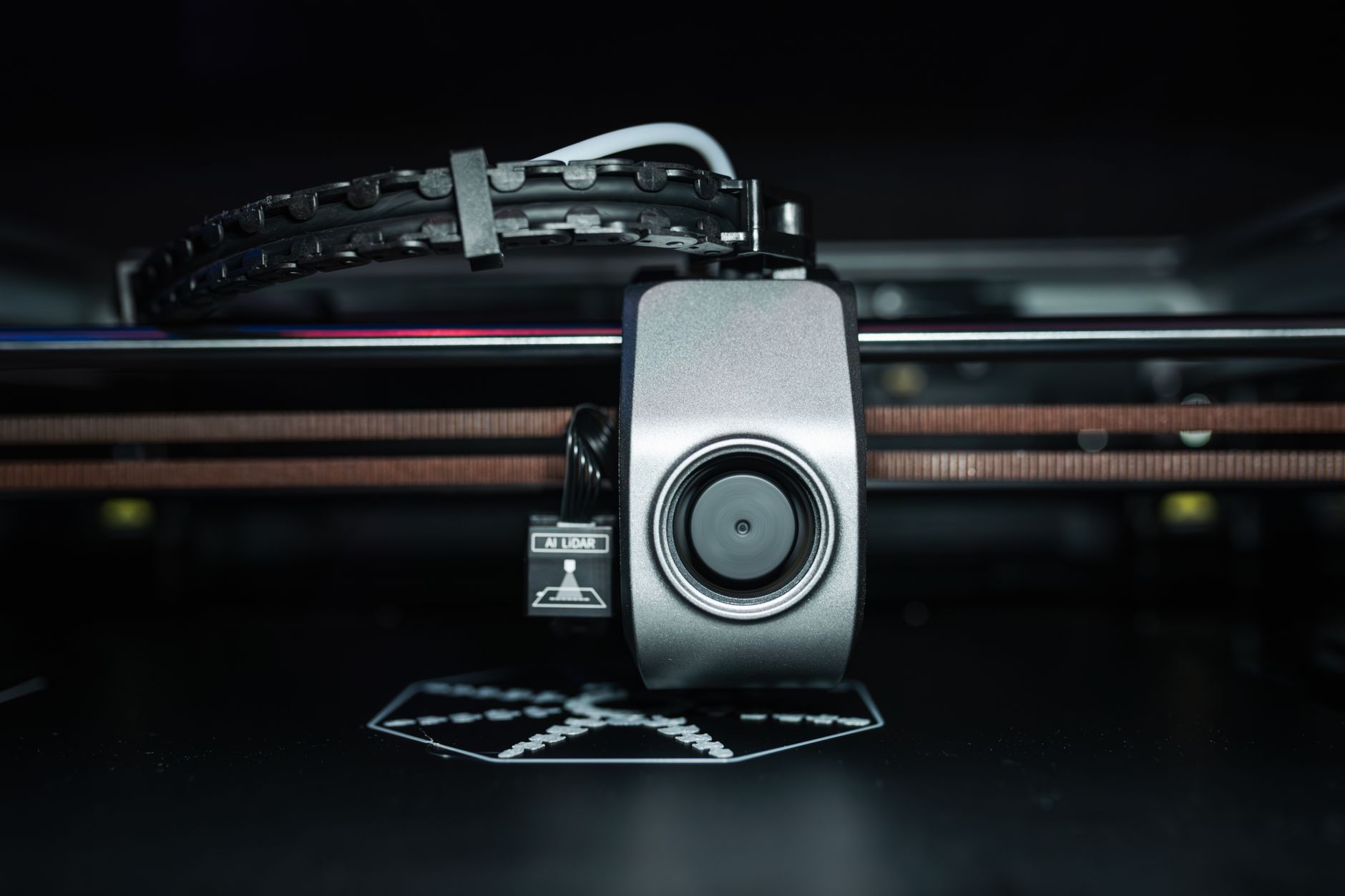 A 3D printer creates a white mechanical gear part on a heated bed