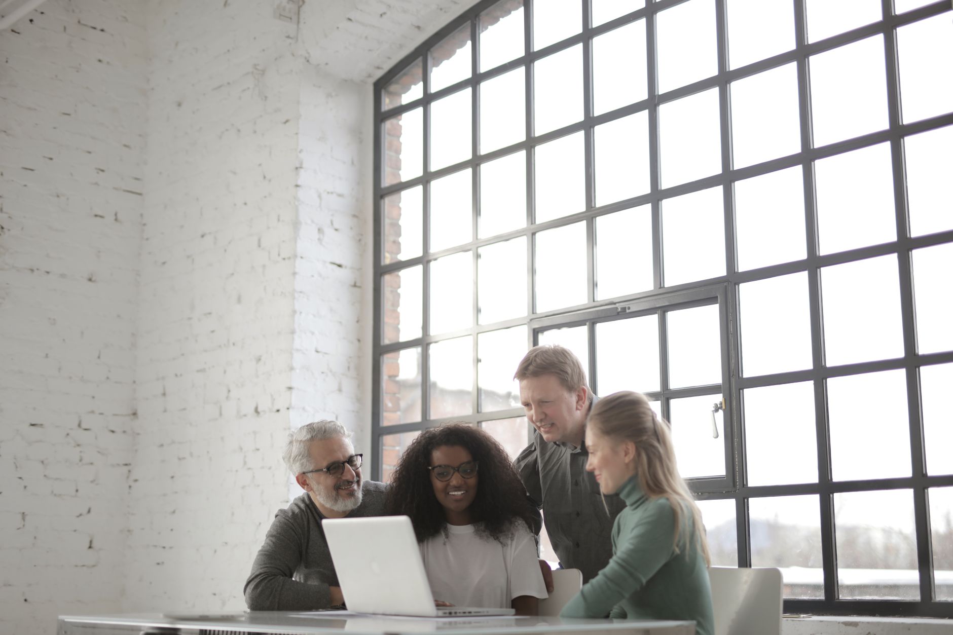 Team members collaborating on a laptop in a modern office setting