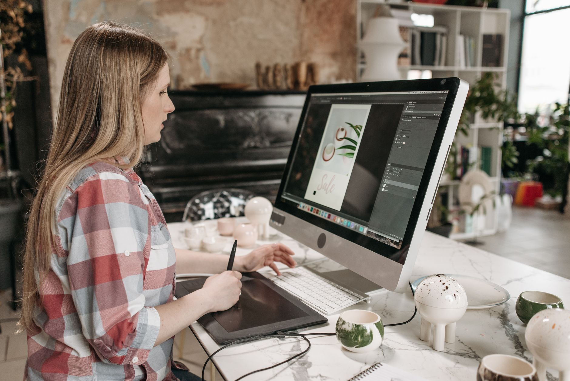 Artist using a stylus on a graphics tablet beside a computer monitor